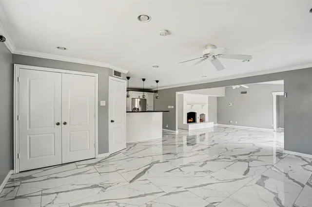 a view of a livingroom with a fireplace a ceiling fan and wooden floor
