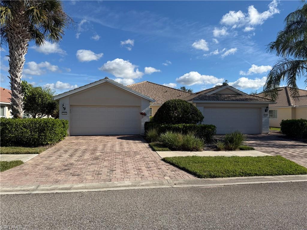 Ranch-style home with stucco siding, decorative driveway, and a tiled roof