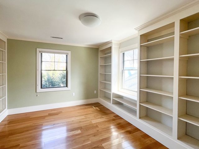 a view of an empty room with a window and wooden floor