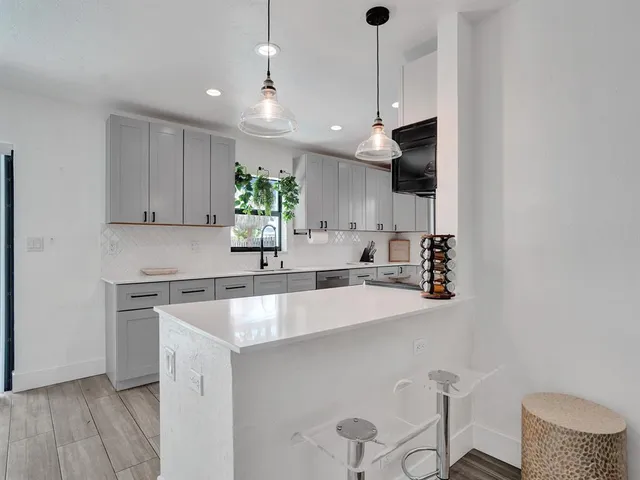 a white kitchen with a sink and a stove top oven with wooden floor