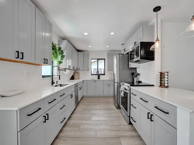 a large kitchen with stainless steel appliances kitchen island granite countertop a sink and dishwasher a stove top oven with wooden floor