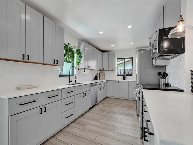 a kitchen with granite countertop a sink stainless steel appliances and cabinets