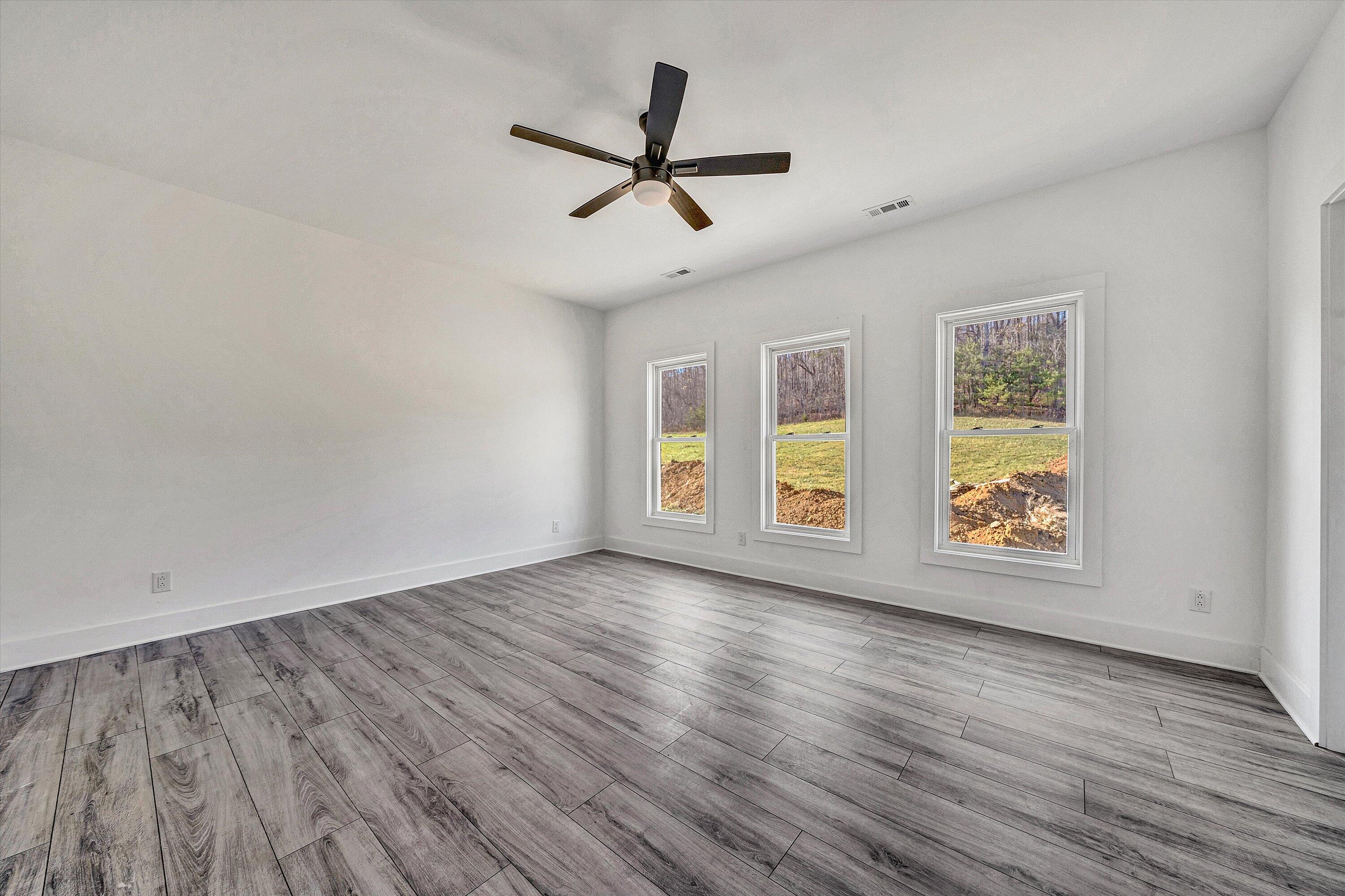 3086 Haymakertown Road Troutville, VA 24175 - Photo 11 of 16 an empty room with wooden floor chandelier fan and windows