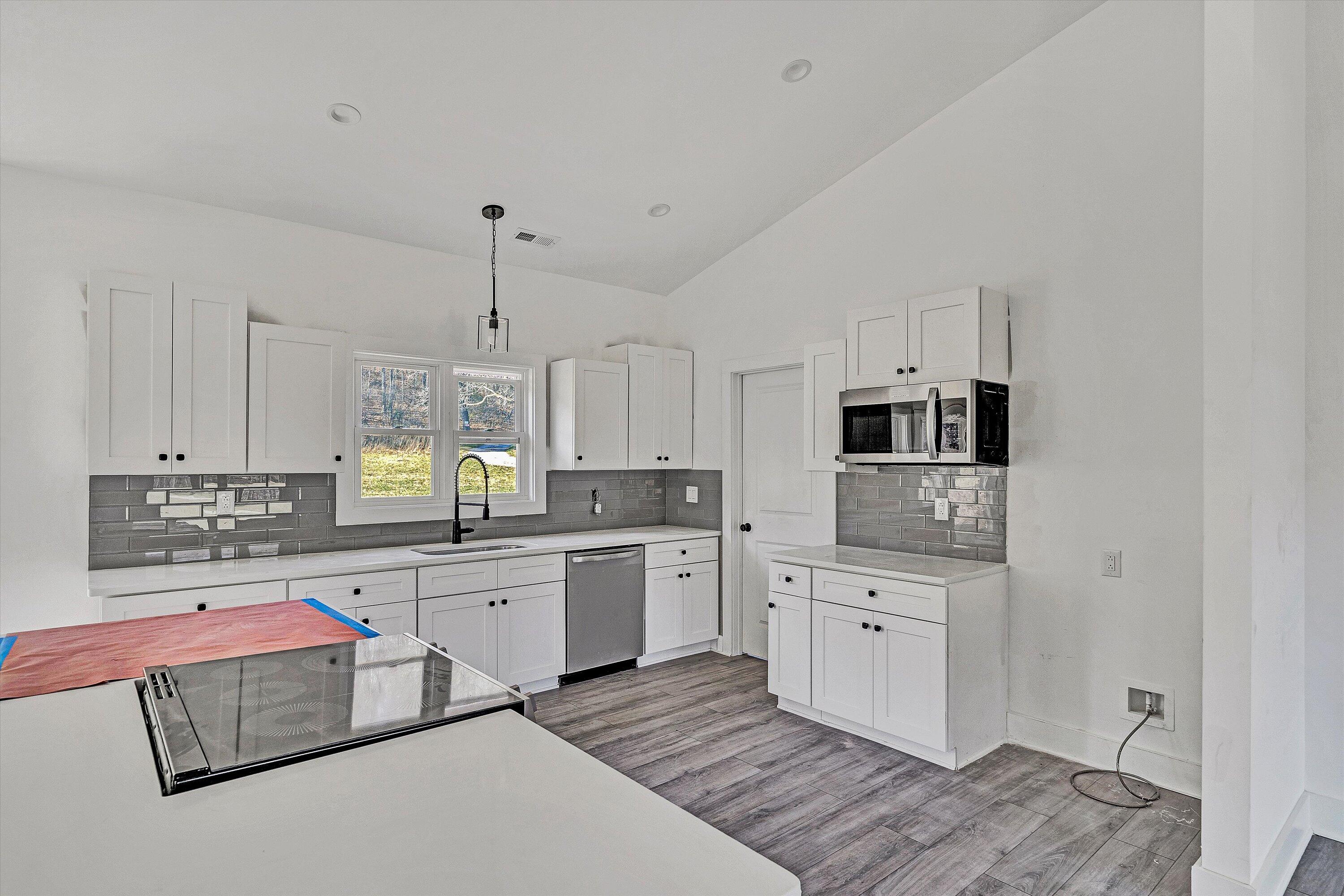 3086 Haymakertown Road Troutville, VA 24175 - Photo 9 of 16 a large white kitchen with a stove a sink dishwasher and a refrigerator with wooden floor