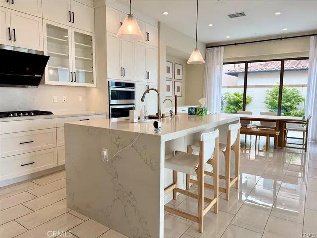 a kitchen with stainless steel appliances kitchen island granite countertop a stove a sink a dining table and chairs with wooden floor