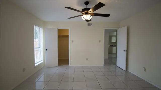 a view of an empty room with a chandelier fan