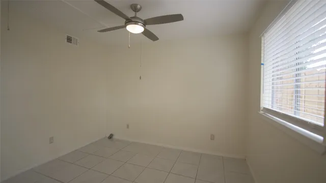 an empty room with a window and a fan