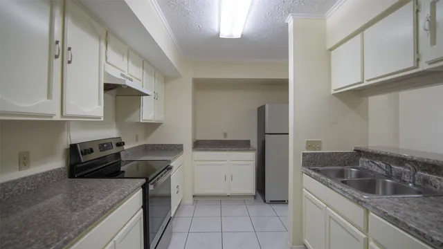 a kitchen with granite countertop a sink a stove and cabinets