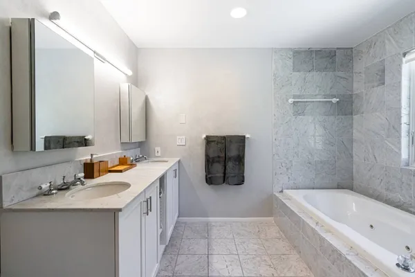 a bathroom with a tub a sink a mirror and a bathtub