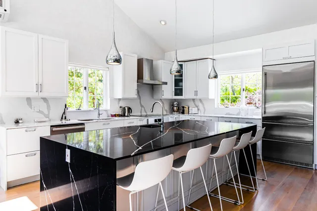 a kitchen with stainless steel appliances granite countertop a sink a stove a refrigerator cabinets and a dining table