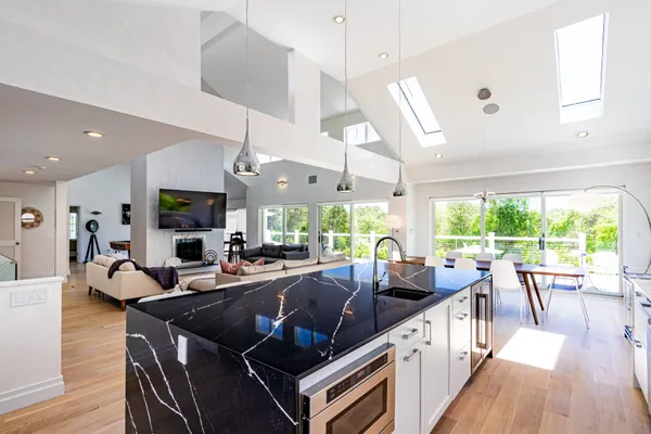 a living room with furniture large windows and wooden floor