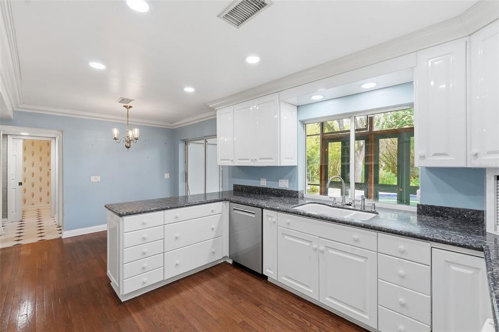 1840 Salem Court Dunedin, FL 34698 - Photo 19 of 64 a kitchen with granite countertop white cabinets and wooden floor