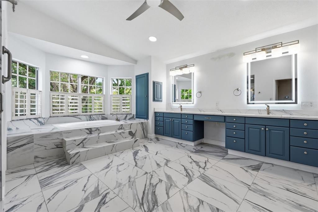 1840 Salem Court Dunedin, FL 34698 - Photo 47 of 64 a spacious bathroom with a double vanity sink a large mirror and a bathtub