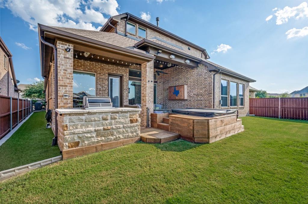 2721 Old Shire Path Road Prosper, TX 75078 - Photo 30 of 39 Brick exterior featuring a covered patio with an outdoor grilling station, a tiered wood-finish deck, and an integrated hot tub