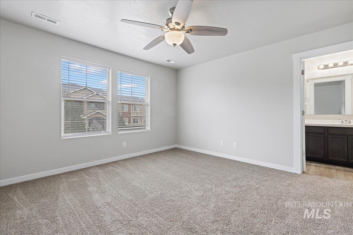2500 East Blue Tick Street Meridian, ID 83642 - Photo 11 of 24 Unfurnished bedroom featuring light colored carpet, a ceiling fan, and ensuite bath