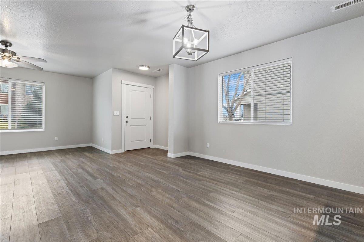 2500 East Blue Tick Street Meridian, ID 83642 - Photo 6 of 24 Unfurnished room featuring a textured ceiling, wood finished floors, a ceiling fan, and hanging lights