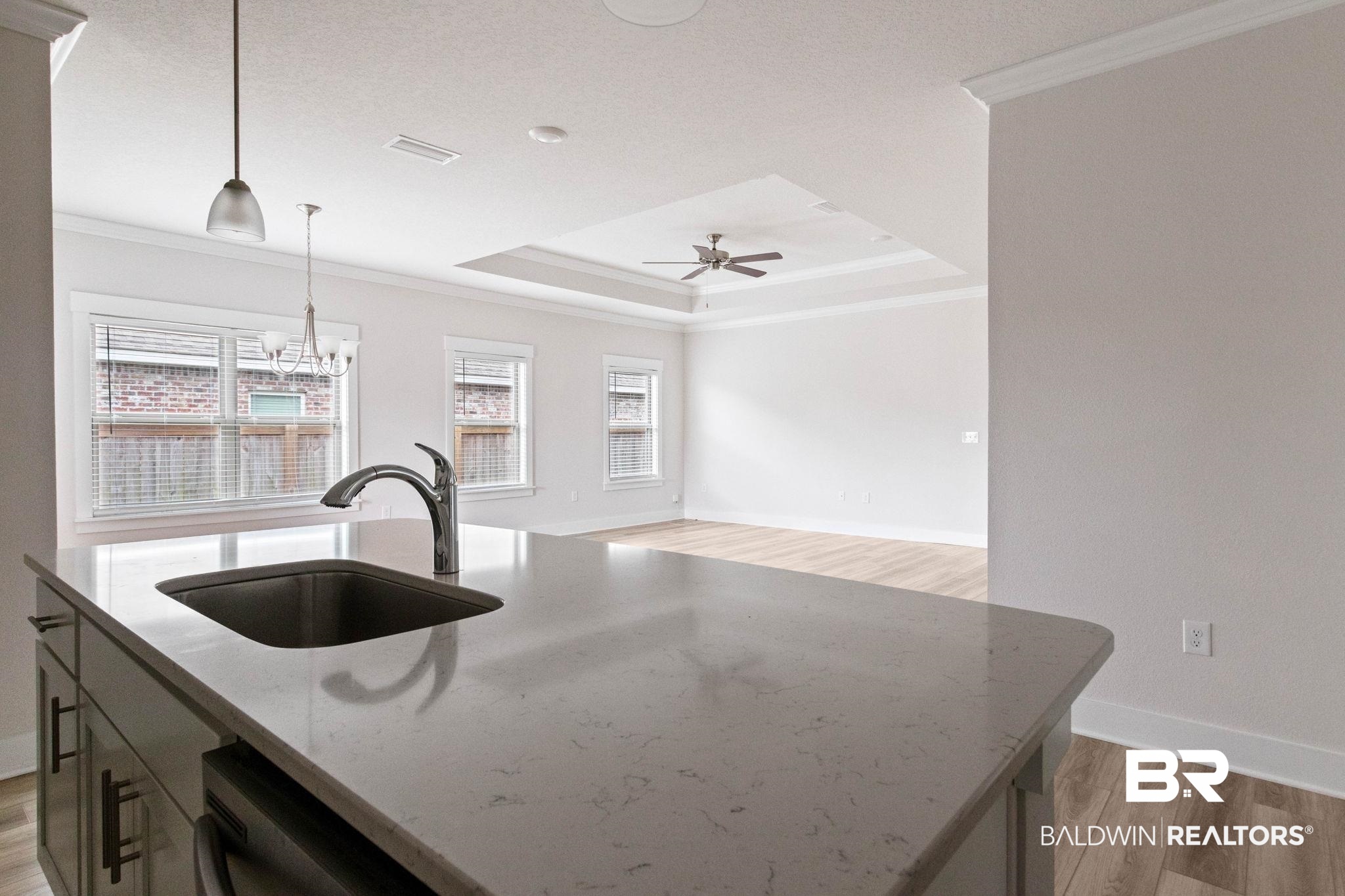 1710 Grouse Street Foley, AL 36535 - Photo 27 of 76 Kitchen island featuring a single basin sink and a high-arc faucet, set against light-toned countertops