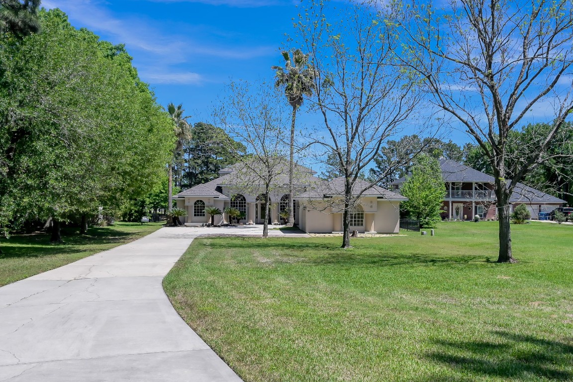 12758 Aries Loop Willis, TX 77318 - Photo 2 of 48 a view of white house with a big yard and large trees