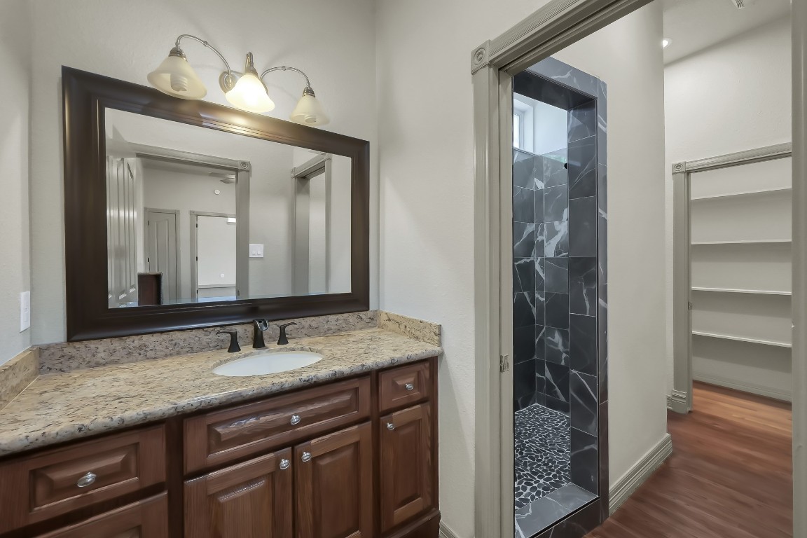 12758 Aries Loop Willis, TX 77318 - Photo 30 of 48 a bathroom with a granite countertop sink a mirror and a shower