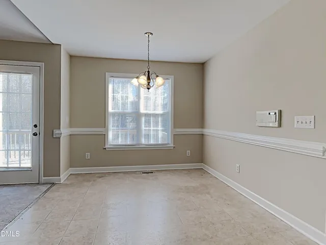 an empty room with chandelier fan and windows