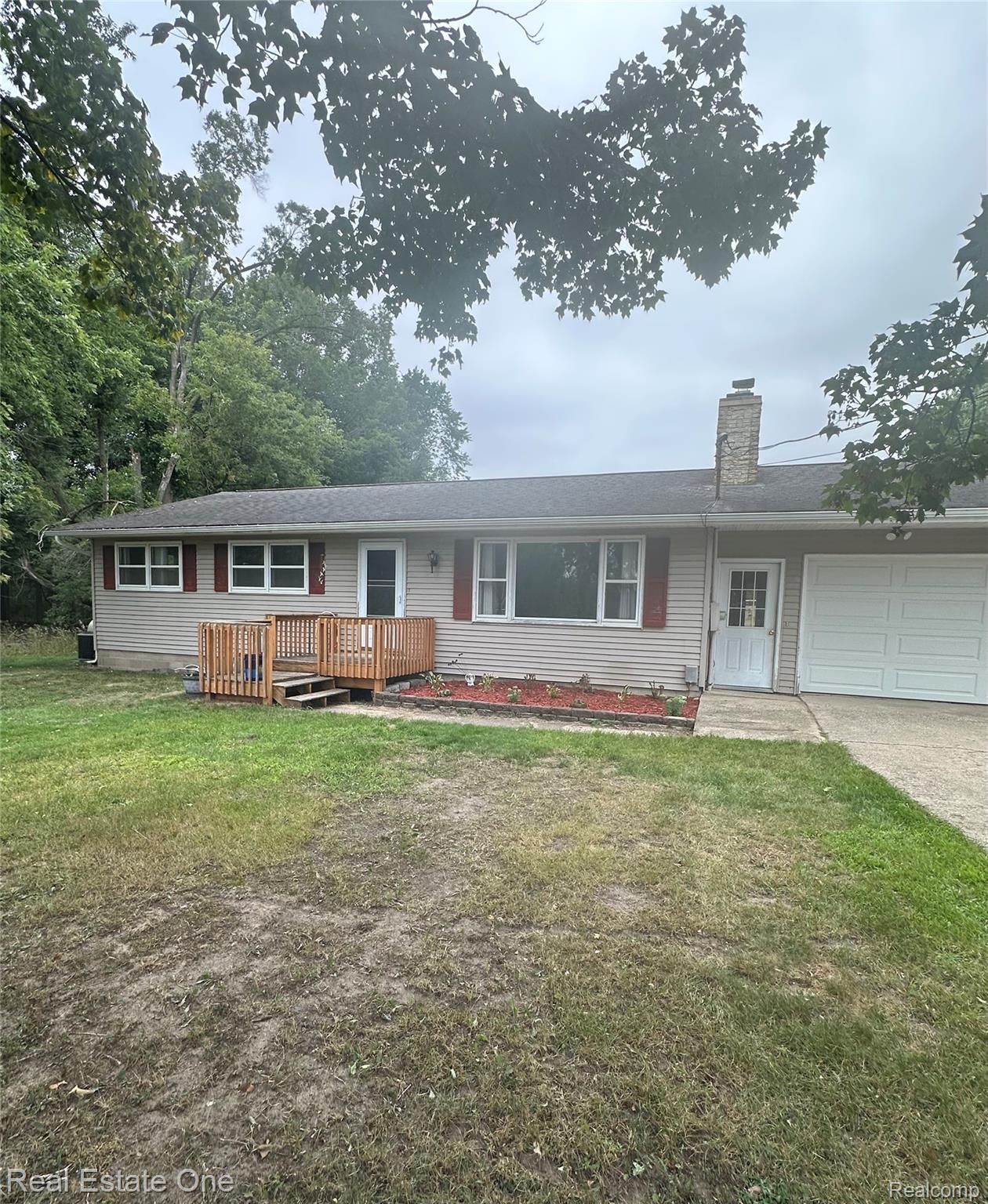 2430 Coolidge Road Barryton, MI 49305 - Photo 4 of 29 Vinyl siding exterior with a wood deck entry, an attached garage, a paved driveway, and a stone chimney