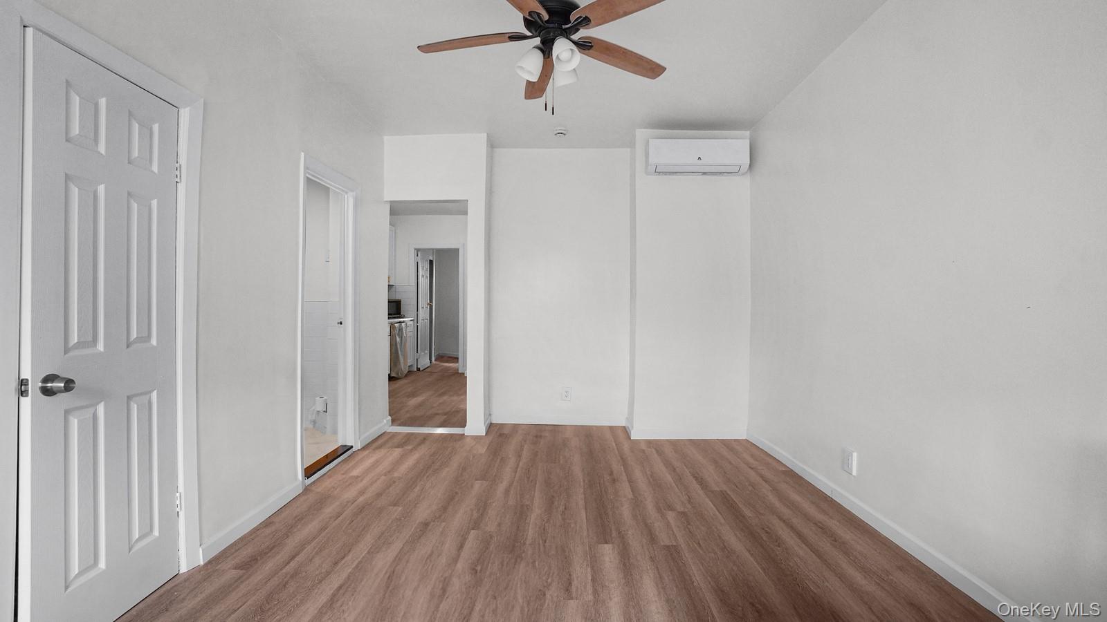 681 Rhinelander Avenue Bronx, NY 10462 - Photo 13 of 30 Unfurnished bedroom with wood finished floors, a ceiling fan, and a wall mounted AC