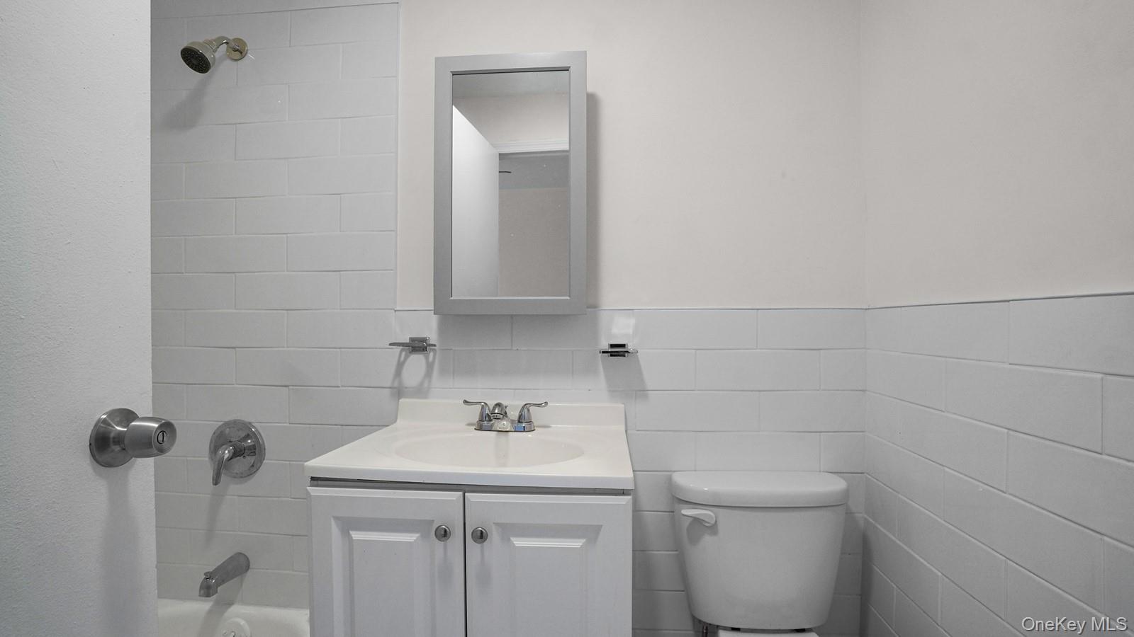 681 Rhinelander Avenue Bronx, NY 10462 - Photo 17 of 30 Bathroom with shower / tub combination, vanity, and tile walls