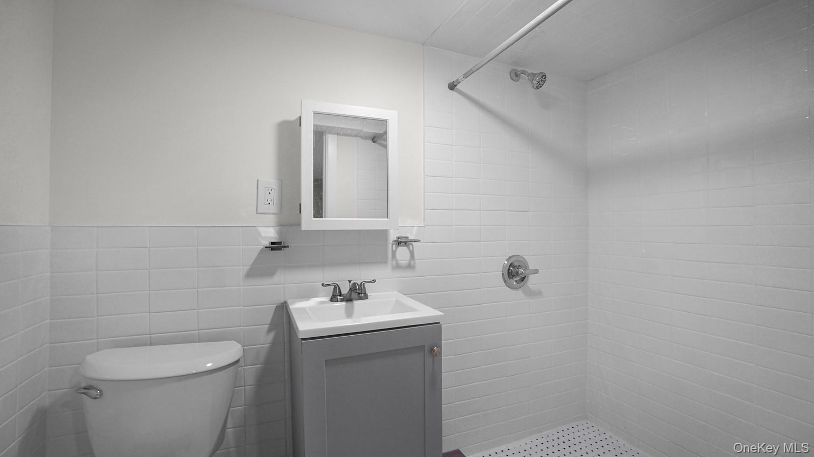 681 Rhinelander Avenue Bronx, NY 10462 - Photo 18 of 30 Full bathroom with a shower stall, tile walls, and vanity
