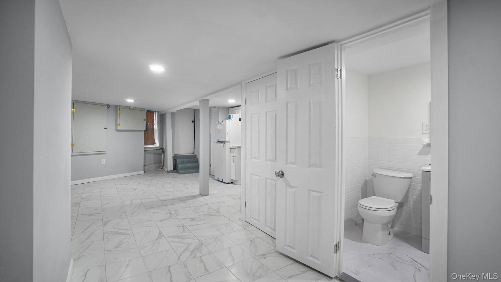 681 Rhinelander Avenue Bronx, NY 10462 - Photo 21 of 30 Bathroom with light marble finish flooring, tile walls, and wainscoting