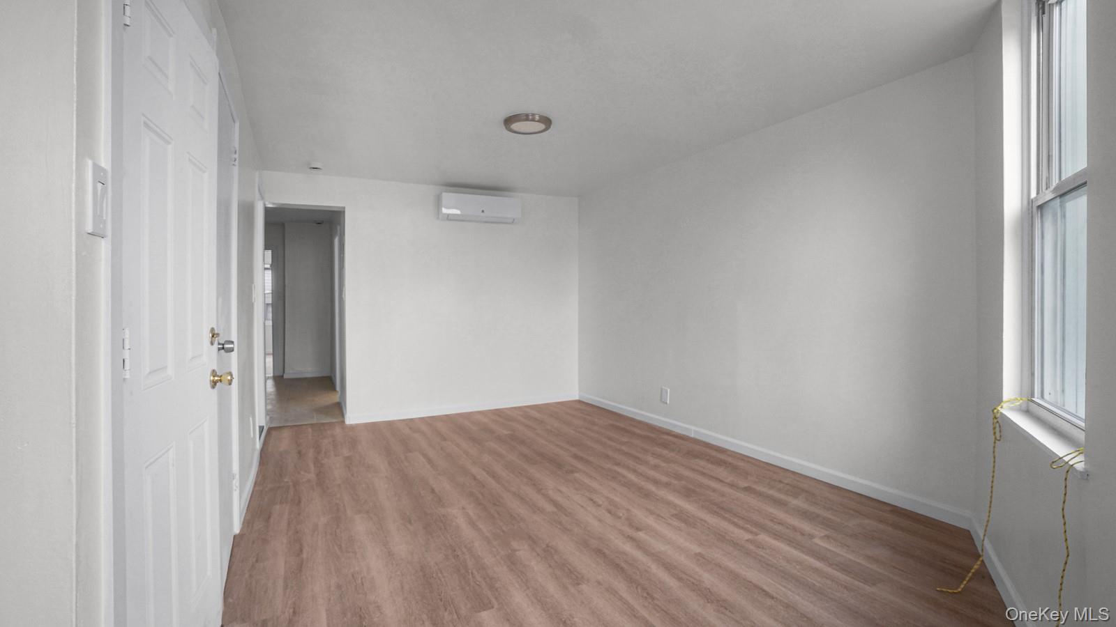 681 Rhinelander Avenue Bronx, NY 10462 - Photo 9 of 30 Unfurnished room featuring light wood finished floors, healthy amount of natural light, and a wall mounted air conditioner