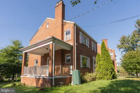 a view of a house with a small yard plants and large tree