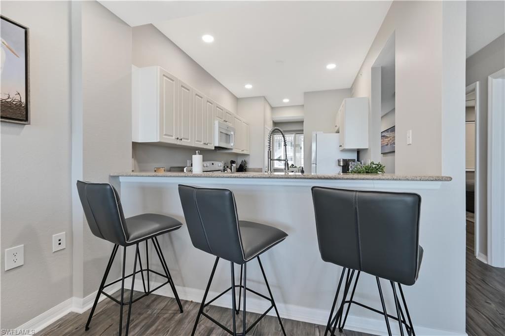 7915 Mahogany Run Lane, Unit 1115 Naples, FL 34113 - Photo 15 of 39 a kitchen with stainless steel appliances kitchen island a table chairs in it and white cabinets