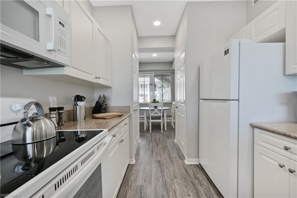 7915 Mahogany Run Lane, Unit 1115 Naples, FL 34113 - Photo 20 of 39 a kitchen with kitchen island granite countertop lots of counter top space and wooden floor