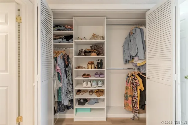 a view of walk in closet with clothes and shoes