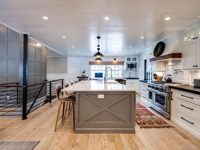 a kitchen with stainless steel appliances granite countertop a sink a stove and a wooden floors