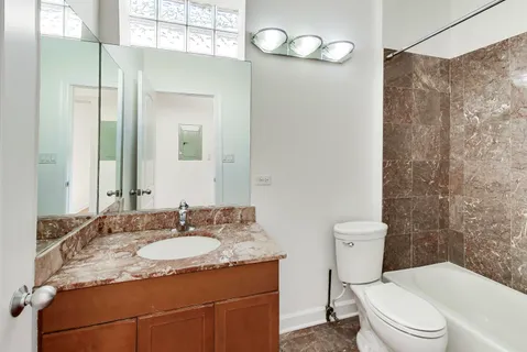 a bathroom with a granite countertop sink mirror vanity and toilet