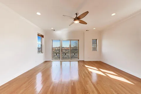 a view of a big room with wooden floor and windows
