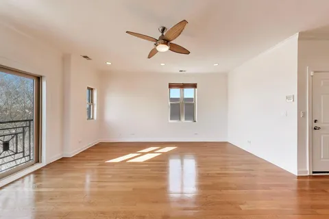 a view of empty room with wooden floor and ceiling fan
