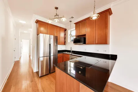 a kitchen with stainless steel appliances granite countertop a refrigerator a stove and a wooden floors