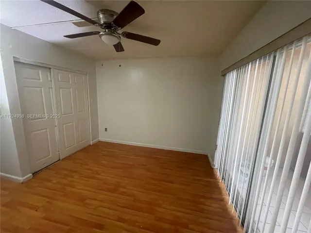 an empty room with wooden floor fan and windows
