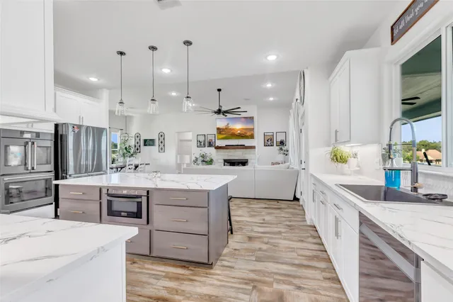 a kitchen with stainless steel appliances kitchen island granite countertop a sink a stove top oven a counter space and cabinets