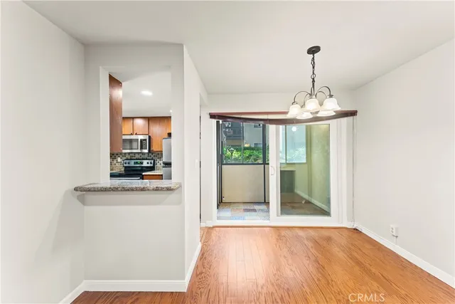 a view of a room with kitchen appliances and wooden floor