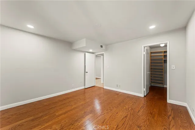 a view of an empty room with wooden floor and closet