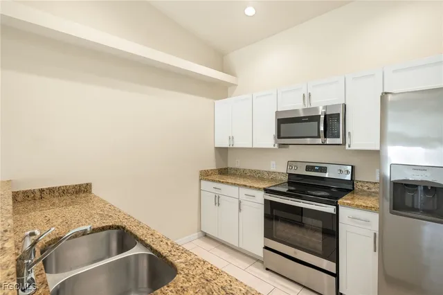 a kitchen with granite countertop a sink stove and microwave