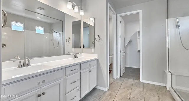 a spacious bathroom with a double vanity sink mirror and shower