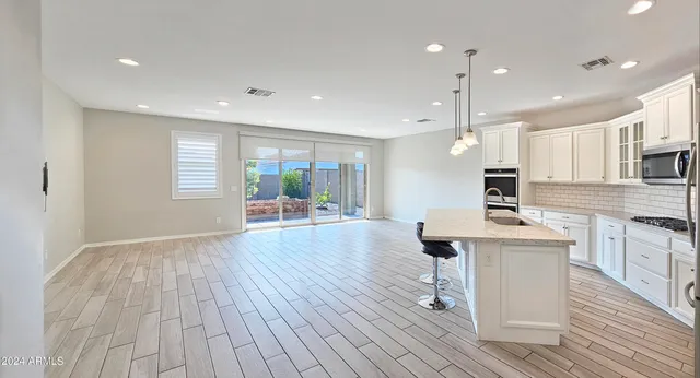 a living room with stainless steel appliances kitchen island hardwood floor and a sink