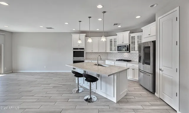 a kitchen with stainless steel appliances kitchen island granite countertop a refrigerator and a sink