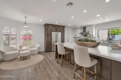 a kitchen with kitchen island granite countertop a counter space chairs stainless steel appliances and cabinets