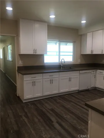 a kitchen with granite countertop white cabinets and sink