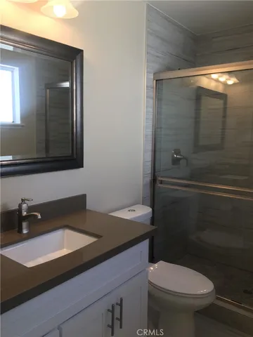 a bathroom with a sink a toilet a shower and mirror